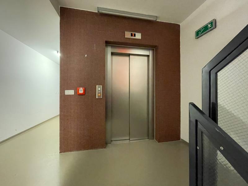 Entrance hall with an elevator, brown mosaic, and emergency exit in a 3-room apartment.