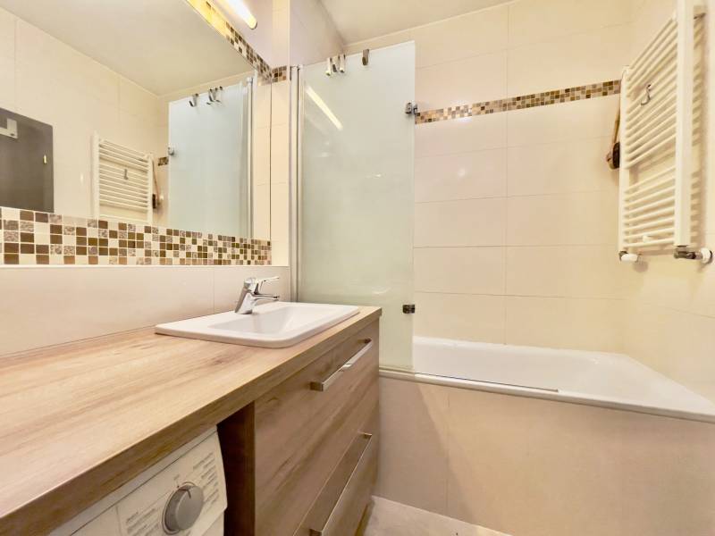 A bathroom with a bathtub, sink, mirror, and decorative tiles in a 3-room apartment.