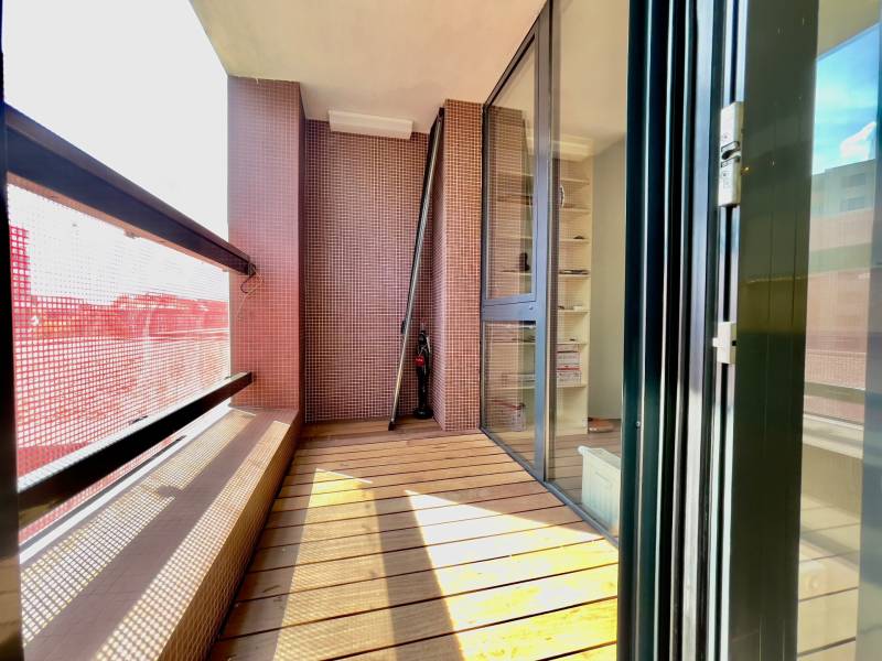 Balcony of a 3-room apartment with a wooden decor floor and a glass partition.