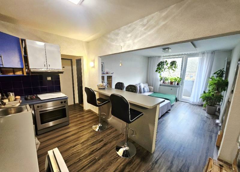 A kitchen connected to the living room with a wooden decor floor in a 3-room apartment.