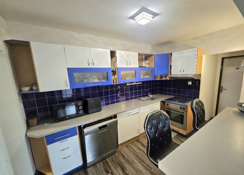 A kitchen in a 3-room apartment with a wooden decor floor and blue details.