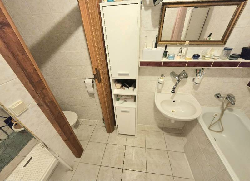 A bathroom in a 3-room apartment with a bathtub, sink, and storage space.