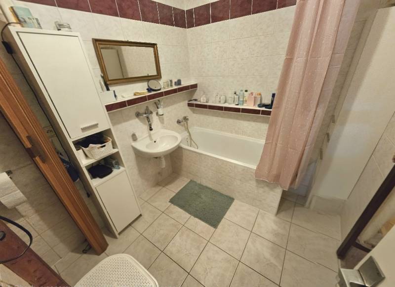 Bathroom in a 3-room apartment with a bathtub, sink, and storage space.