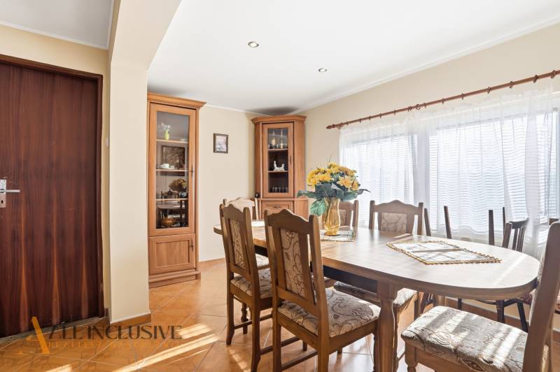 Dining room in a cottage with wooden furniture, a large table, and a bright interior.