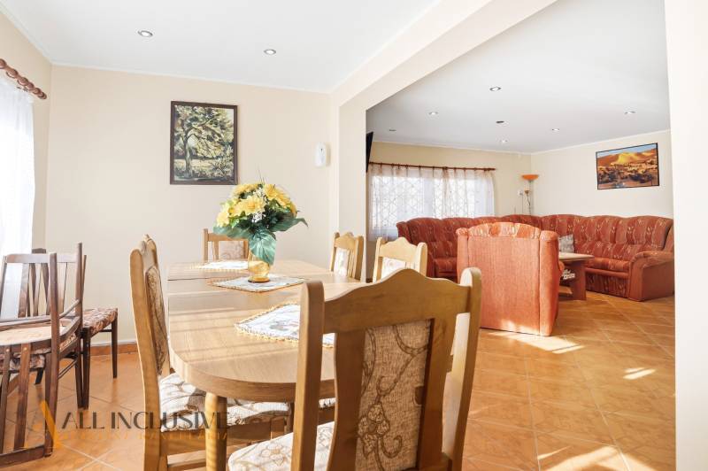 Interior of a cottage with a dining table, floral decoration, and a comfortable sofa.