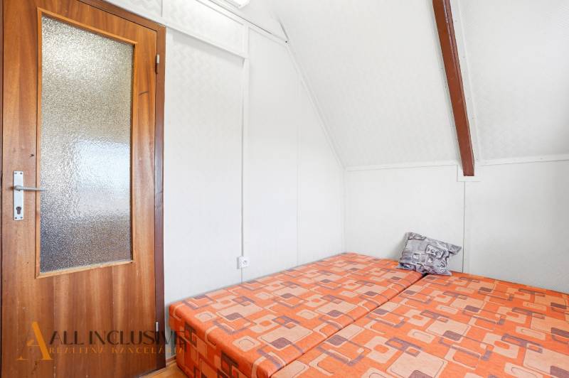 Wooden door, bed with colorful bedding, and white ceiling in the cottage.