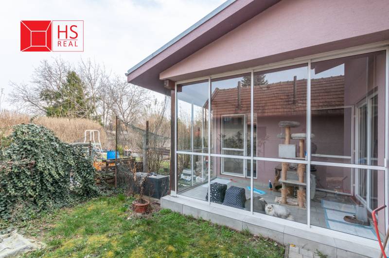 A family house in Šurany with a glass veranda and a garden full of greenery.