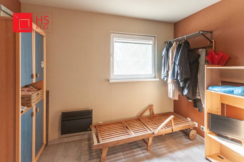 A room in a family house with shelves, a hanger, and simple furniture.