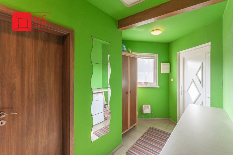 Entrance hall in a family house with green walls and a mirror.