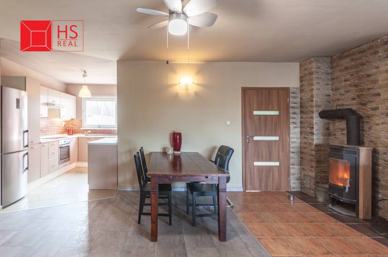 Dining room with a brick wall, fireplace, and kitchen in a family house.