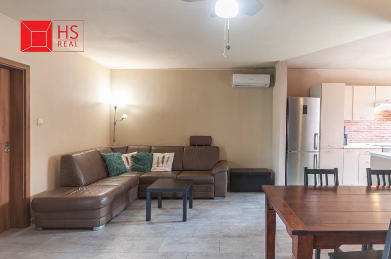 Living room in a family house with a leather sofa and air conditioning, next to the kitchen.