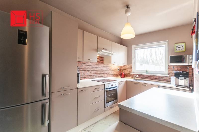A kitchen in a family house with brick cladding and light furniture.