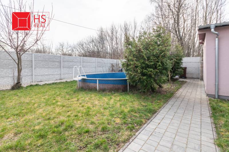 The garden of a family house in Šurany with a swimming pool, walkway, and trees.