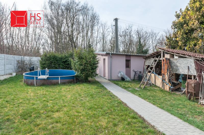 The garden of a family house in Šurany with a pool and a shelter, surrounded by greenery.