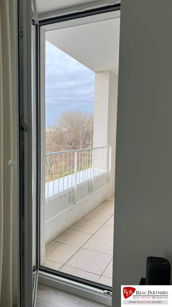 View from the room to the balcony of a 2-room apartment overlooking greenery.