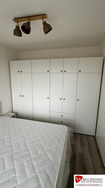 Bedroom in a two-room apartment with a large wardrobe and a floor with a wooden decor.