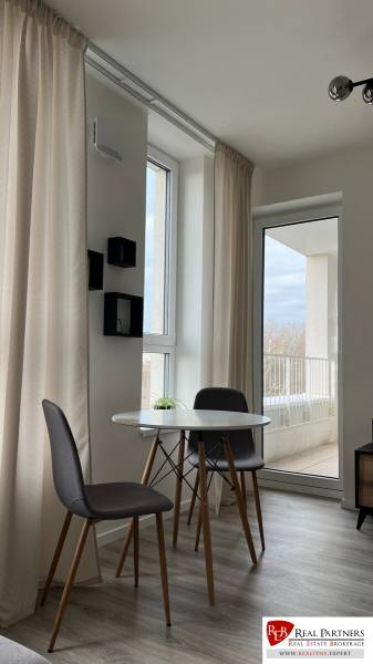 A dining area with a round table and chairs in a 2-room apartment.