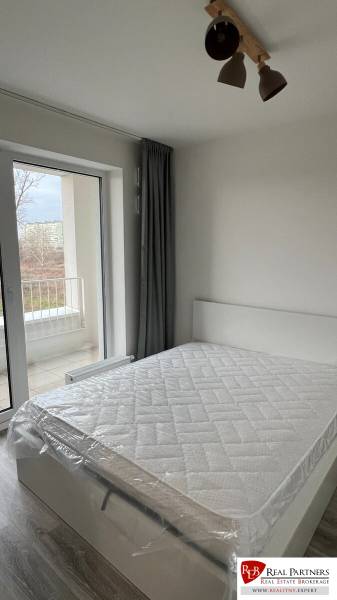 Bedroom with a bed and curtains in a 2-room apartment, floor with wooden decor.