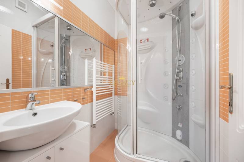 Modern bathroom with a bathtub, sink, and orange tiles in a family house.