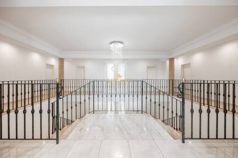 The interior of a family house with a dominant chandelier and metal railing.
