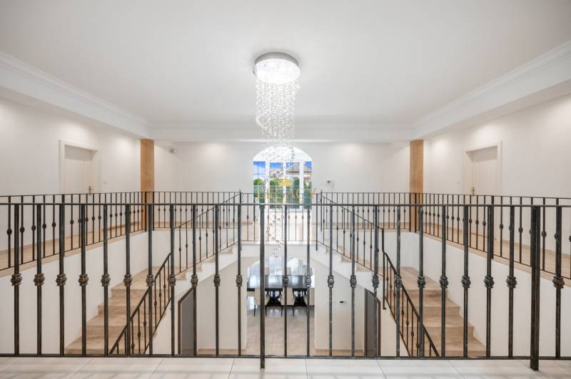 A staircase in a family house with a metal railing and a hanging light fixture.