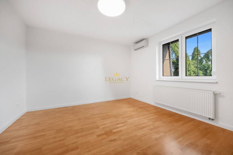 A bright room with wood-patterned flooring, air conditioning, and a radiator in a family house.