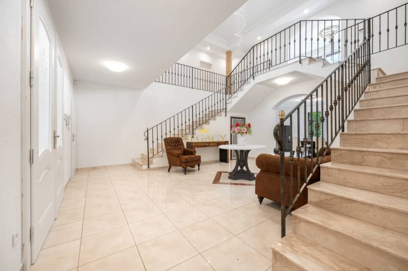 The interior of a family house with a spiral staircase, a brown armchair, and blooming flowers on the table.