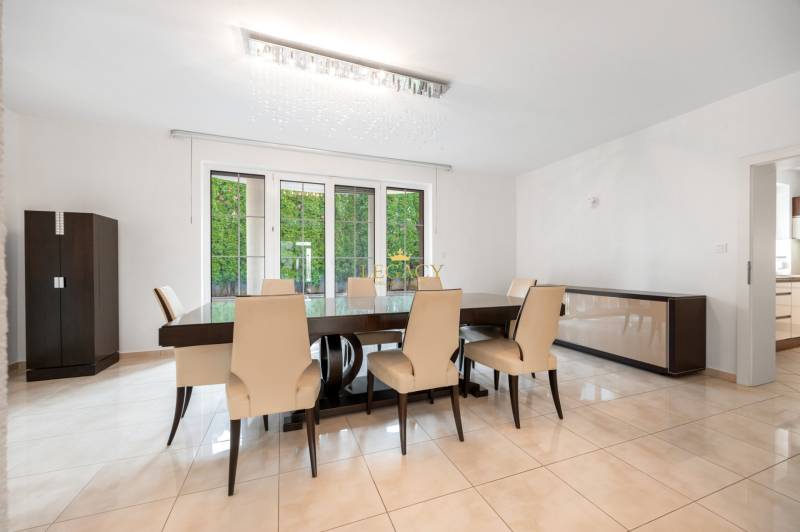 Dining room in a family house with a large table, cream chairs, view of the garden.