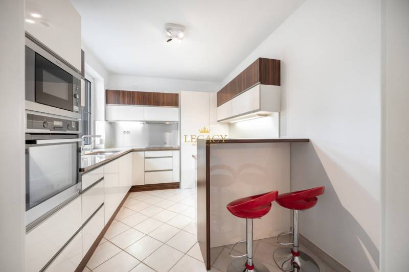 A kitchen in a family house with a modern bar counter and red chairs.