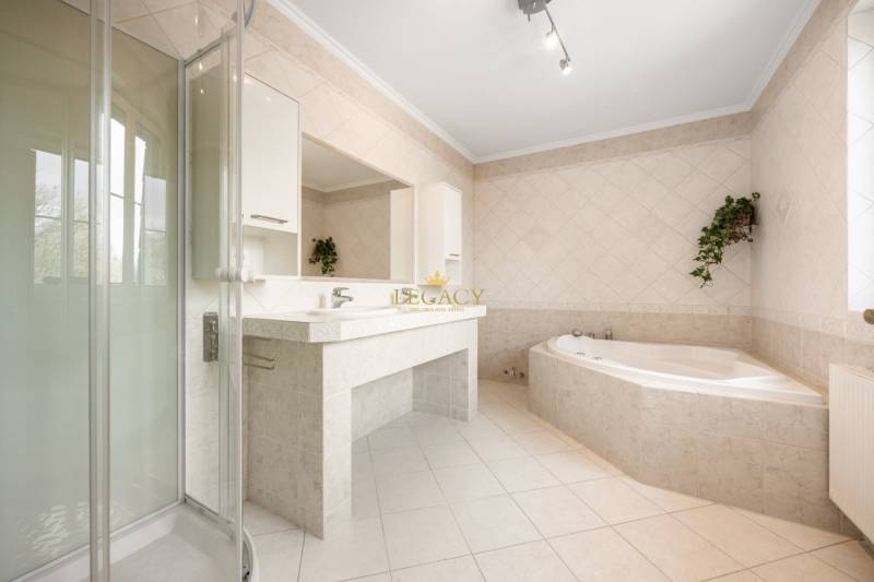 Bathroom with a bathtub and a shower in a family house with tiled flooring.