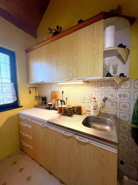 A kitchen in a cottage with wooden decor, light countertops, yellow walls.