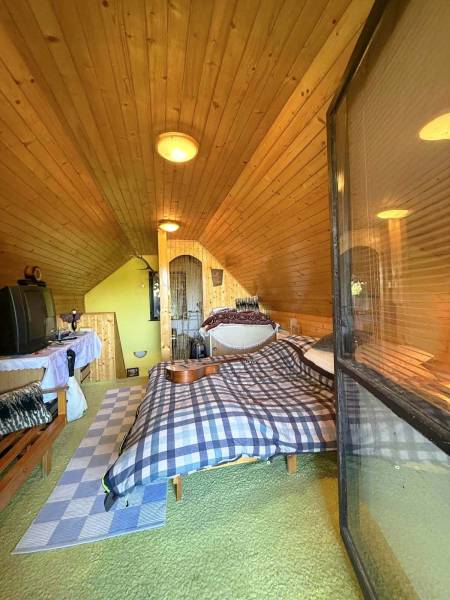 Attic room in a cottage with wooden walls and a bed, simple furnishings.