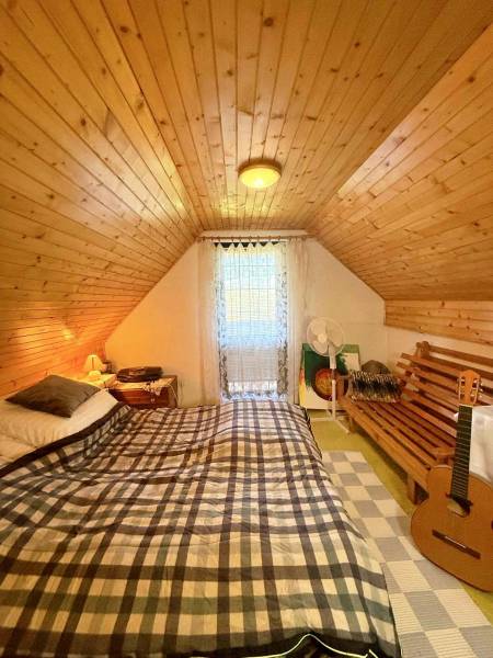 Attic room in a cottage with a bed, wooden beams, and a guitar.