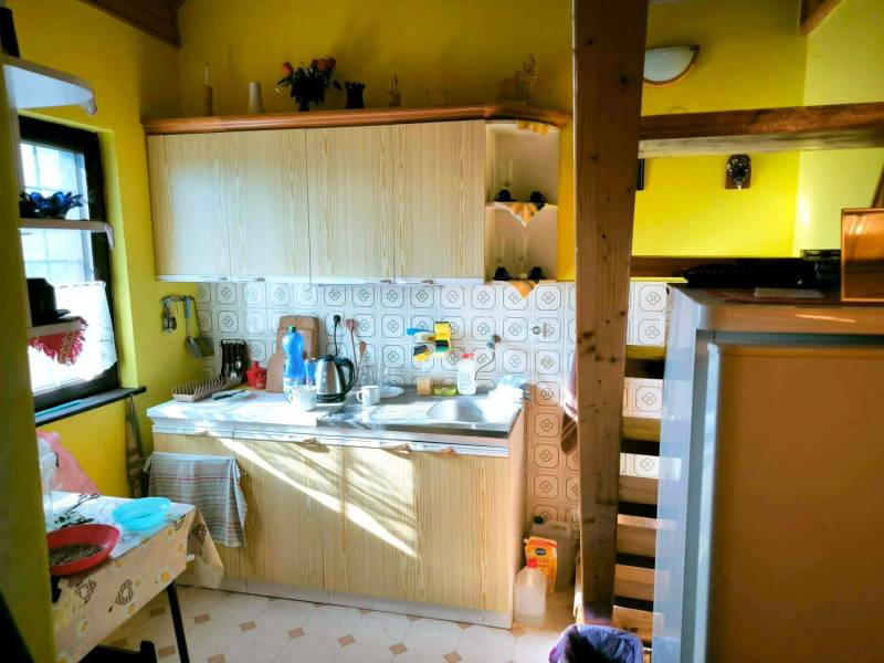 A kitchen in a cottage with wooden decoration, retro tiles, and yellow walls.