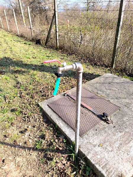 There is an outdoor water faucet by the fence at the exterior of the cottage in Malé Kršteňany.