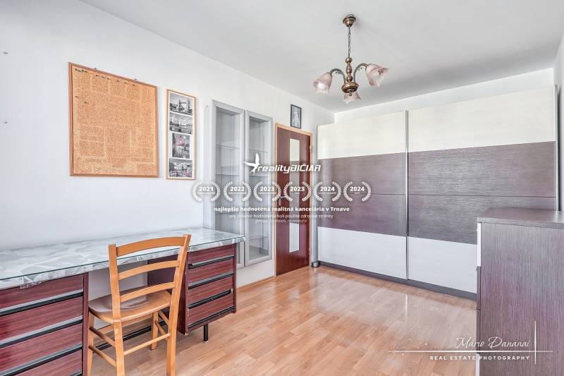 A room in a 3-room apartment with a desk, a floor with a wooden decor, and a wardrobe.