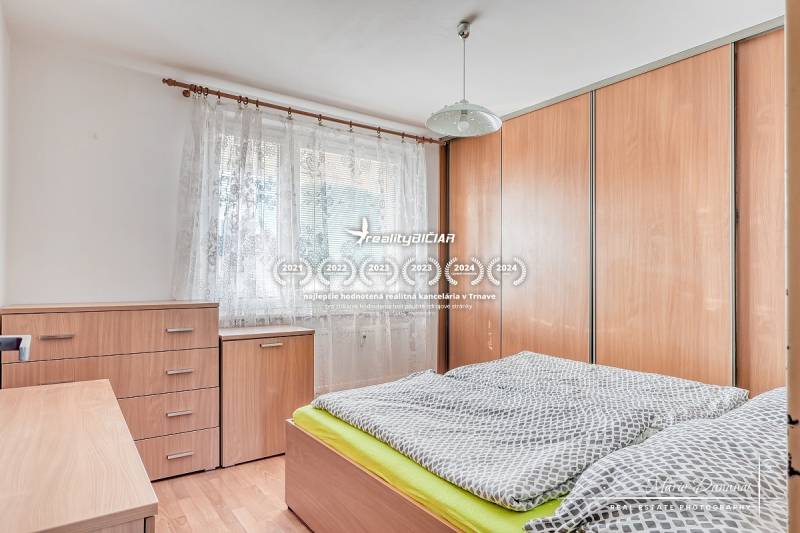 Bedroom in a 3-room apartment with wood-patterned flooring, wardrobe, bed, furniture.