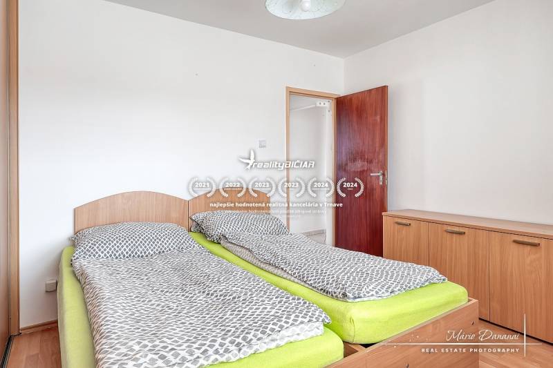 A bedroom in a 3-room apartment with two beds and a wooden decor floor.