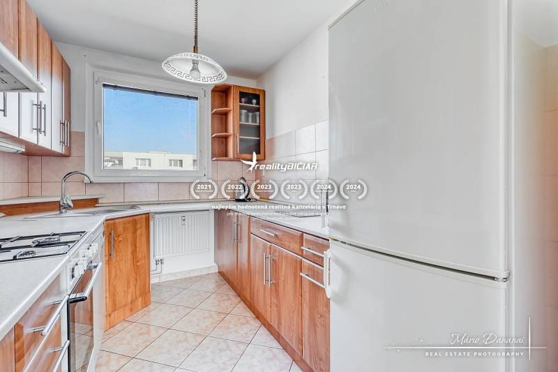 A kitchen in a 3-room apartment with a wooden decor floor, equipped with a sink and a stove.