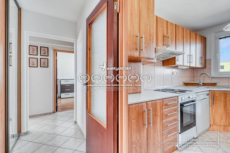 A kitchen with wooden decor and a hallway in a 3-room apartment with a built-in wardrobe.