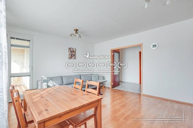 Interior of a 3-room apartment with a wooden decor floor, dining table, and sofa.