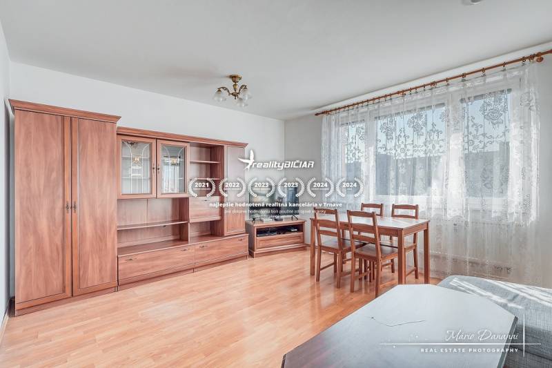 Living room in a three-room apartment with a wooden decor floor, furniture, and a dining table.
