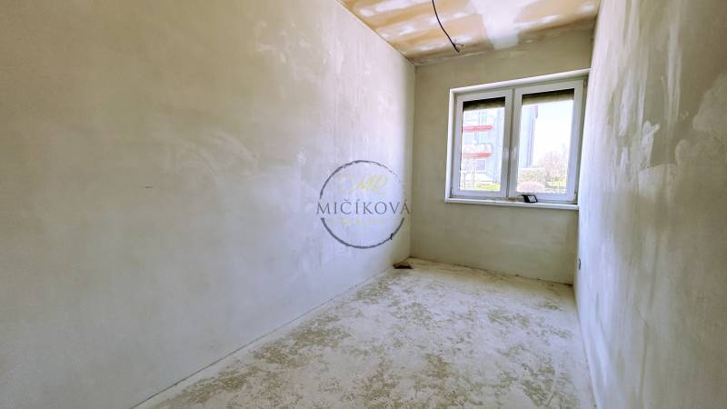A room in a family house with a window and plastered walls, without floor covering.