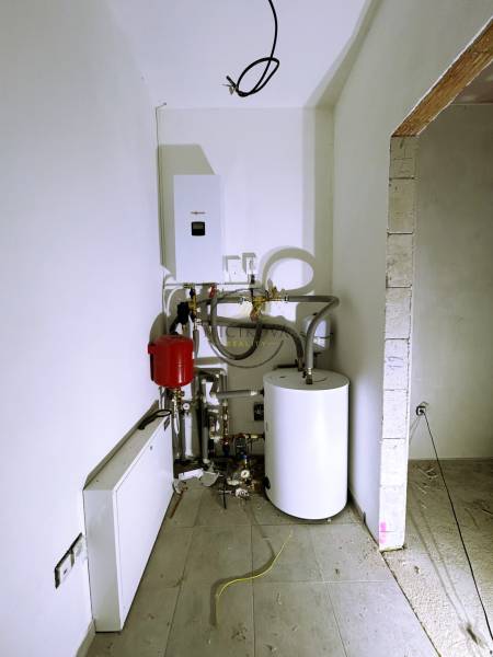 A technical device in a family house with a connected boiler and pipes.