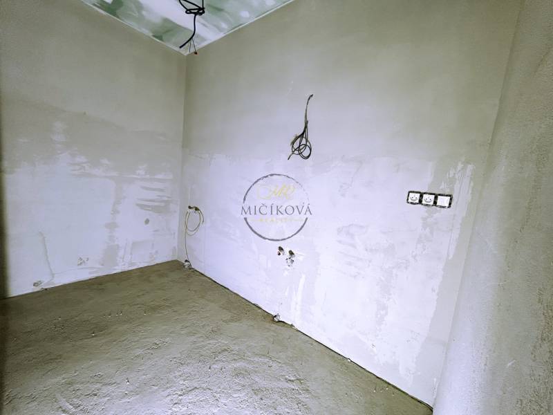 An unfinished room in a family house with exposed electrical installations and white wall paint.