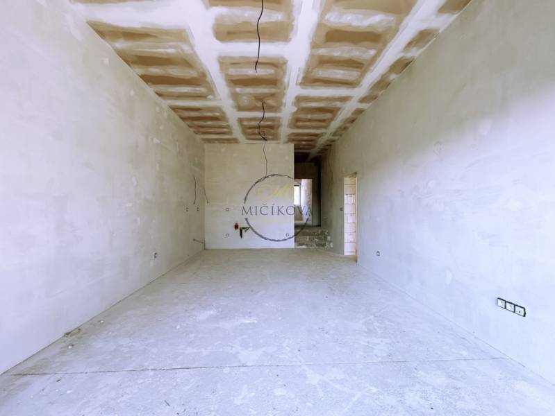 A spacious room in a family house without finished flooring and wall painting.