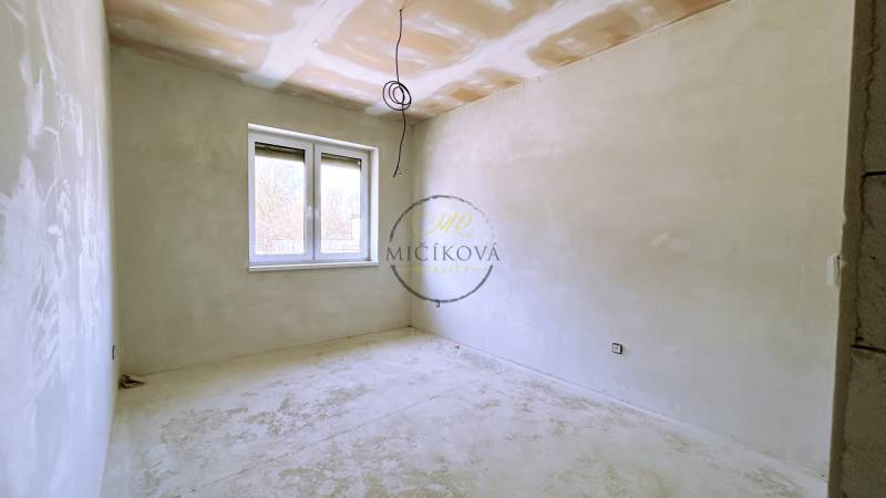 Unfinished room in a family house with a window and white walls.