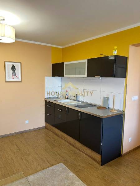 A kitchen with dark cabinets, wood-patterned flooring, and a yellow wall.