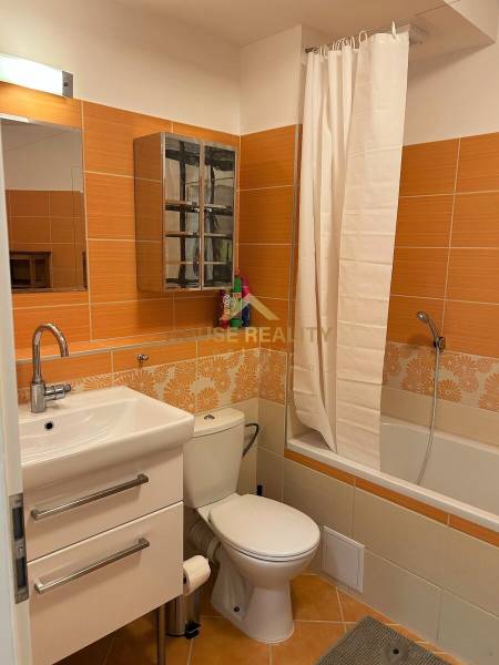 A bathroom with orange and white tiles, a bathtub, a sink, and a toilet in a 3-room apartment.