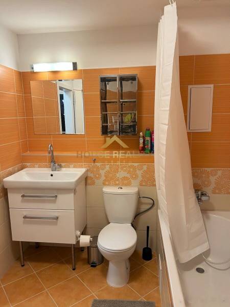 A bathroom with orange tiles, a bathtub, a sink, and a toilet in a 3-room apartment.